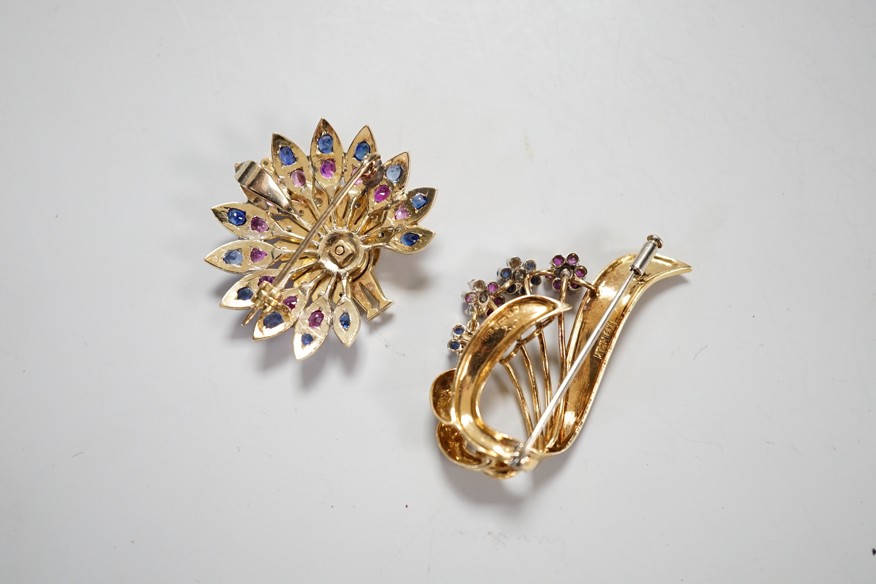 A modern Italian 18k, ruby, sapphire and diamond set floral spray brooch, 42mm and a yellow metal and gem set peacock brooch, gross weight 25.6 grams.